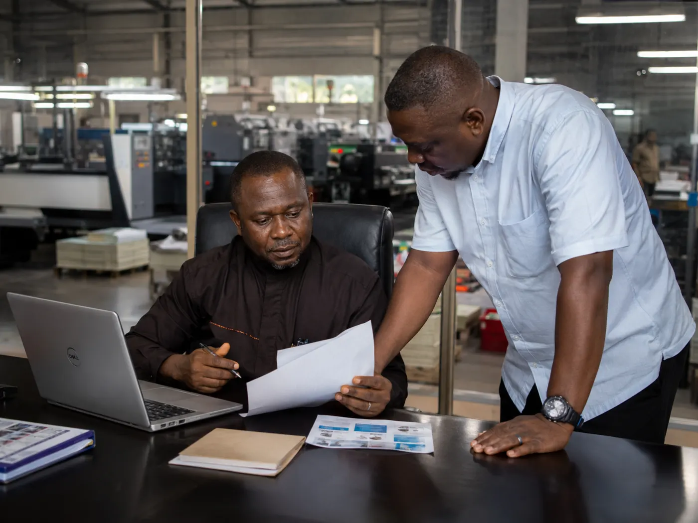 African production team reviewing documents inside a factory office