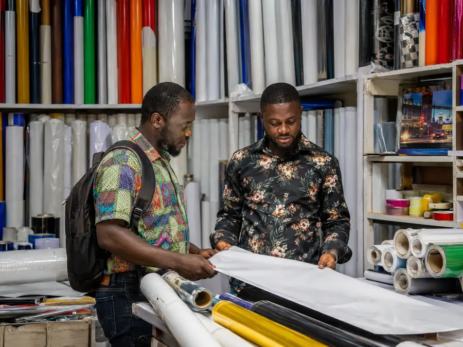 Two men reviewing sheet material in a production supplies shop